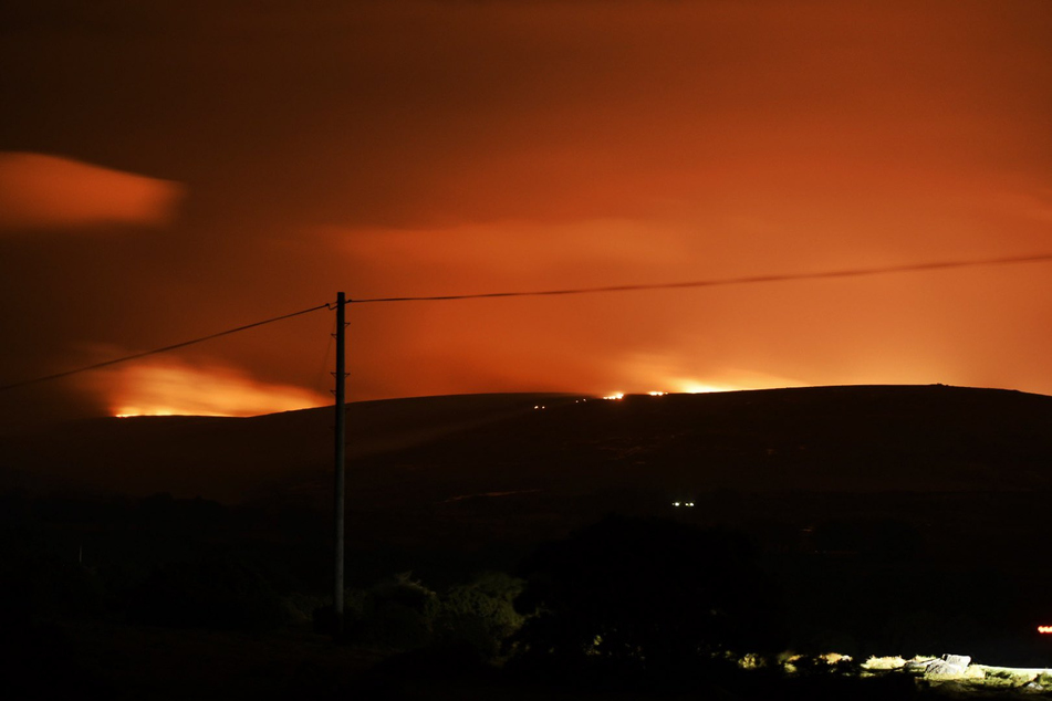 Feuer ist am Horizont zu sehen, das im Dartmoor in der englischen Grafschaft Devon ausgebrochen ist. Die Moor- und Heidelandschaft ist für ihre bronzezeitlichen Gräber und Siedlungsspuren wie beispielsweise Steinkreise bekannt.