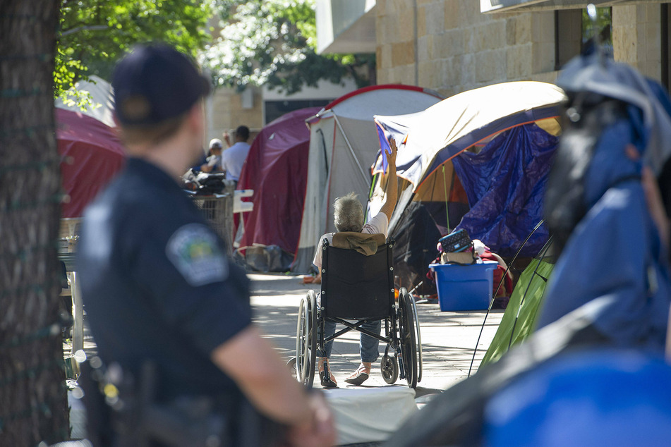Austin police officers monitor the clean-up process at a homeless encampment around City Hall in Austin, Texas, on June 14, 2021.