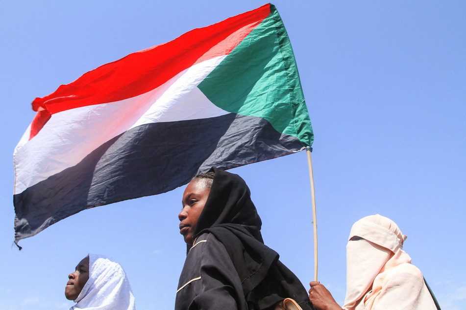 Students from schools in Khartoum hold up the Sudanese flag during a November 3, 2025, protest against atrocities committed by the Rapid Support Forces against the people of El- Fasher.