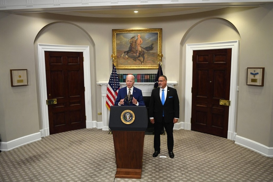 Secretary of Education Miguel Cardona watches on as Biden makes his remarks.