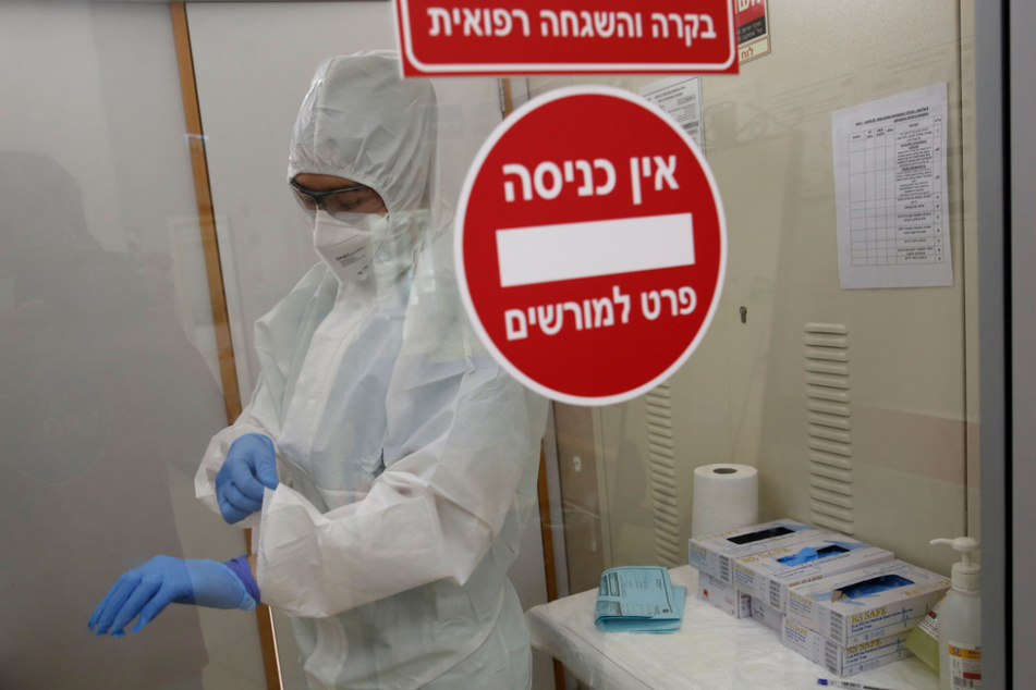 Ein medizinischer Mitarbeiter des Krankenhauses "Yitzhak Shamir Medical Center" in Tel Aviv zieht auf der Corona-Station den Ärmel seiner Schutzkleidung zurecht. Die Zahl der Neuinfektionen mit dem Coronavirus ist in Israel stark gestiegen.