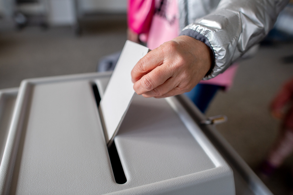 Eine Wählerin wirft in einem Wahllokal einen Stimmzettel für die Bundestagswahl in eine Wahlurne.