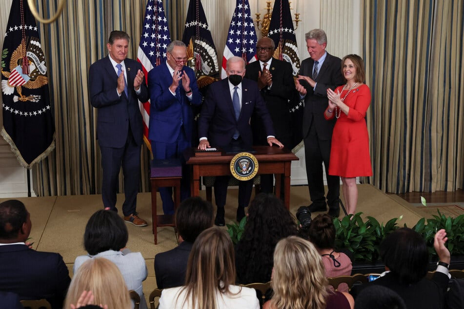 Democratic Party members applaud after Biden's singing of the IRA.