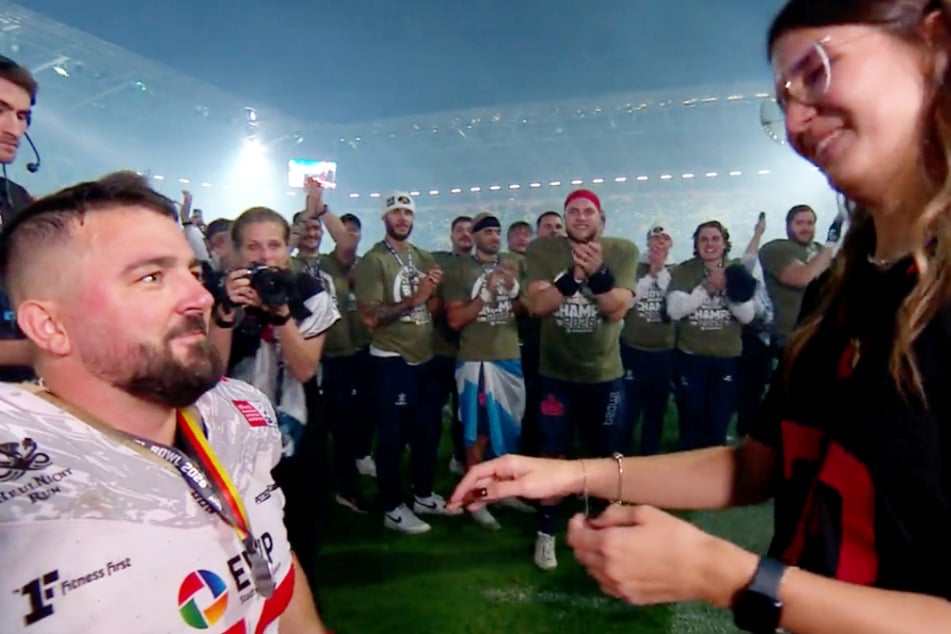 Live im TV auf DF1 machte Nemanja Graovac (l.) seiner Freundin einen Antrag. Im Hintergrund freuten sich die Monarchs mit.