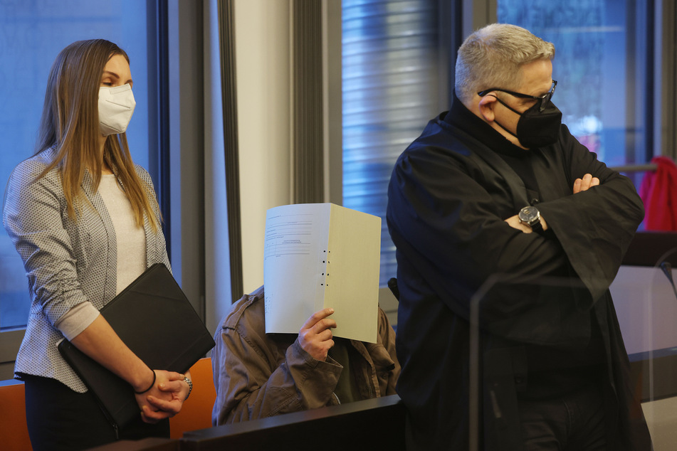 Der Angeklagte (46) verbirgt im Wuppertaler Gerichtssaal sein Gesicht hinter einem Ordner. Der 46-Jährige wurde wegen doppelten Totschlags zu 14 Jahren Haft verurteilt.