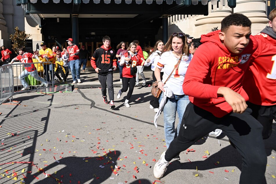 People flee after shots were fired near the Kansas City Chiefs' Super Bowl LVIII victory parade on Wednesday in Kansas City, Missouri. Two men have been charged with murder in connection with the shooting that left one person dead and 22 wounded, officials said Tuesday.