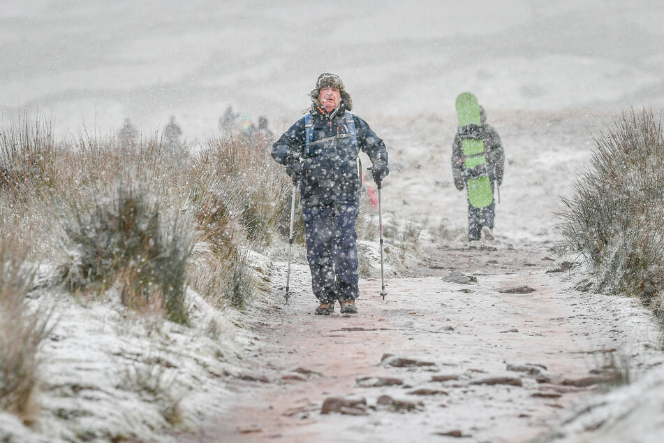 Ein Mann mit Nordic Walking-Stöcken wandert, als Schnee fällt.