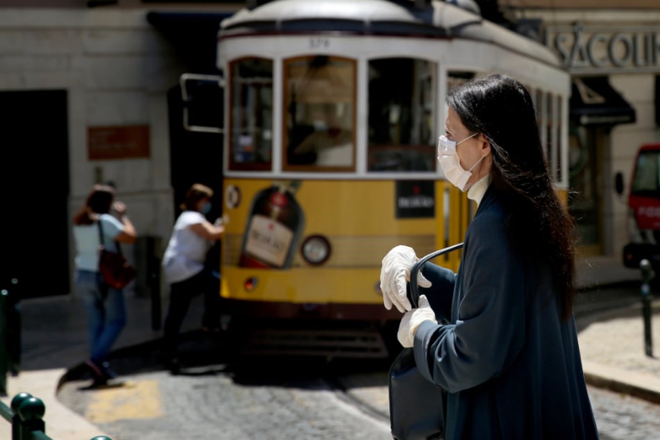 Portugal, Lissabon: Eine Passantin trägt einen Mundschutz und Schutzhandschuhe.