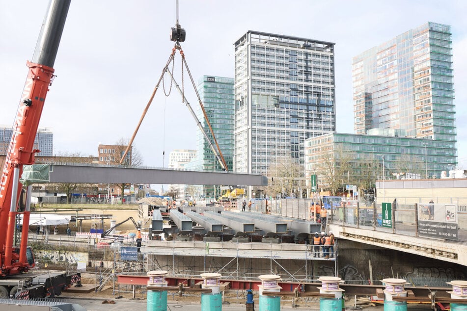 Ein Kran hebt einen Stahlträger auf der Baustelle der Berlinertordammbrücke ein.