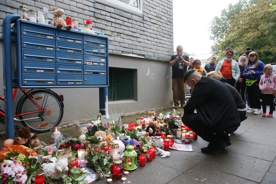 Trauende knien vor Blumen, Kerzen und Stofftieren vor dem Haus in Solingen, in dem am Vortag fünf tote Kinder aufgefunden worden waren.
