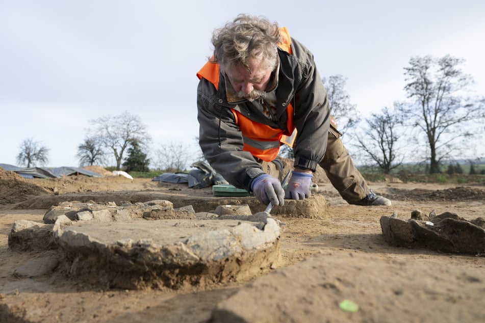 Svenn Gebauer vom Landesamt für Archäologie Sachsen bei der Arbeit. Mit einem Pinsel räumt er ein Urnengrab aus der Spätbronzezeit von Erde frei.