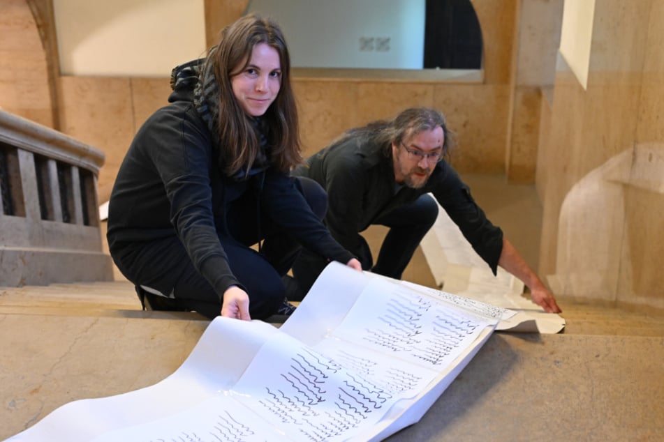 Tina Kreller (35) und Tobias Möller (47) entrollten im Rathaus eine über 60 Meter lange Papierrolle.