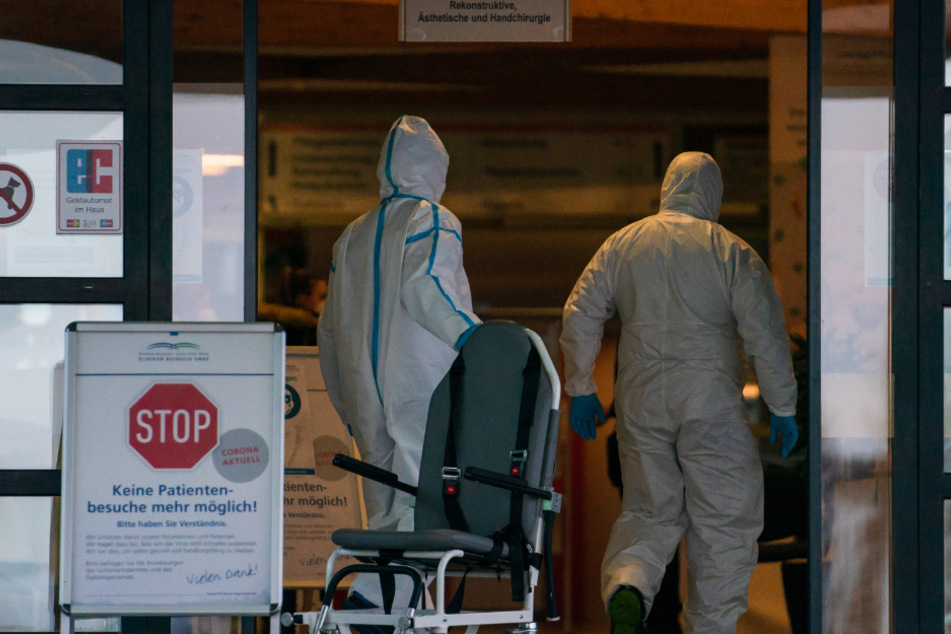 Bayreuth: Medizinisches Personal in Ganzkörperschutzanzügen geht in Richtung Haupteingang des Klinikums Bayreuth. Wegen des Verdachts des Ausbruchs einer hochansteckenden Corona-Mutation hat das Klinikum Bayreuth betroffene Häuser vorerst geschlossen.