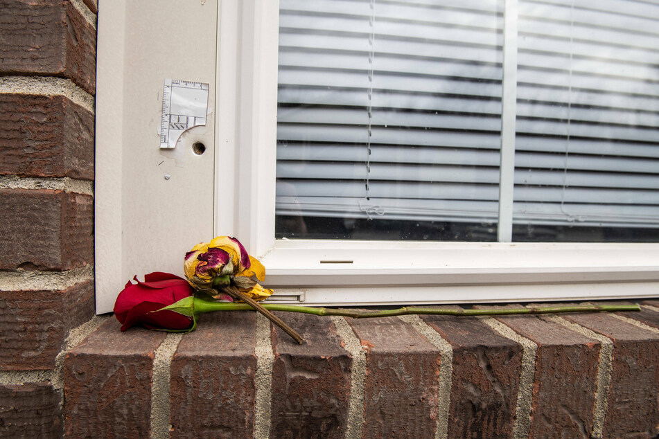 Two roses lie on the windowsill below a bullet hole outside the apartment where Breonna Taylor was shot by LMPD.