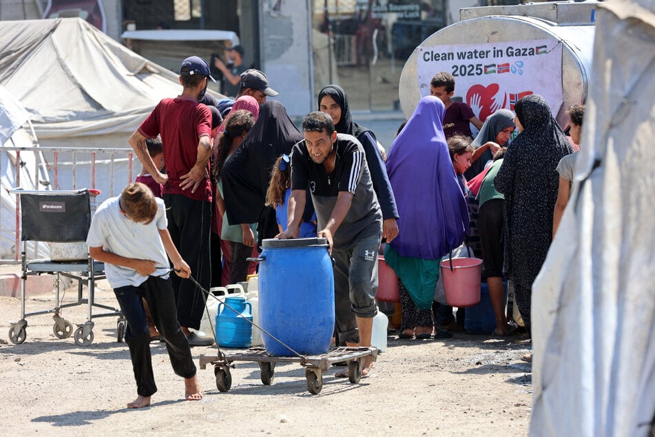Palestinians transport gallons of clean water from a distribution point in Gaza City on August 1, 2025.