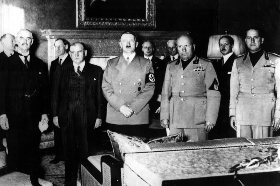 Adolf Hitler (M.) steht am 29.09.1938 in München bei der Unterzeichnung eines Abkommens über die Abtretung des sudetendeutschen Gebiets an das Deutsche Reich. Mit dem Impf-Zertifikat hat er jedoch nichts zu tun.