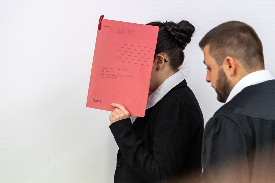 Die Angeklagte Jennifer W., die sich der Terrormiliz Islamischer Staat (IS) im Irak angeschlossen haben soll, hält sich beim Betreten des Gerichtssaals einen roten Aktendeckel vors Gesicht. (Archiv)