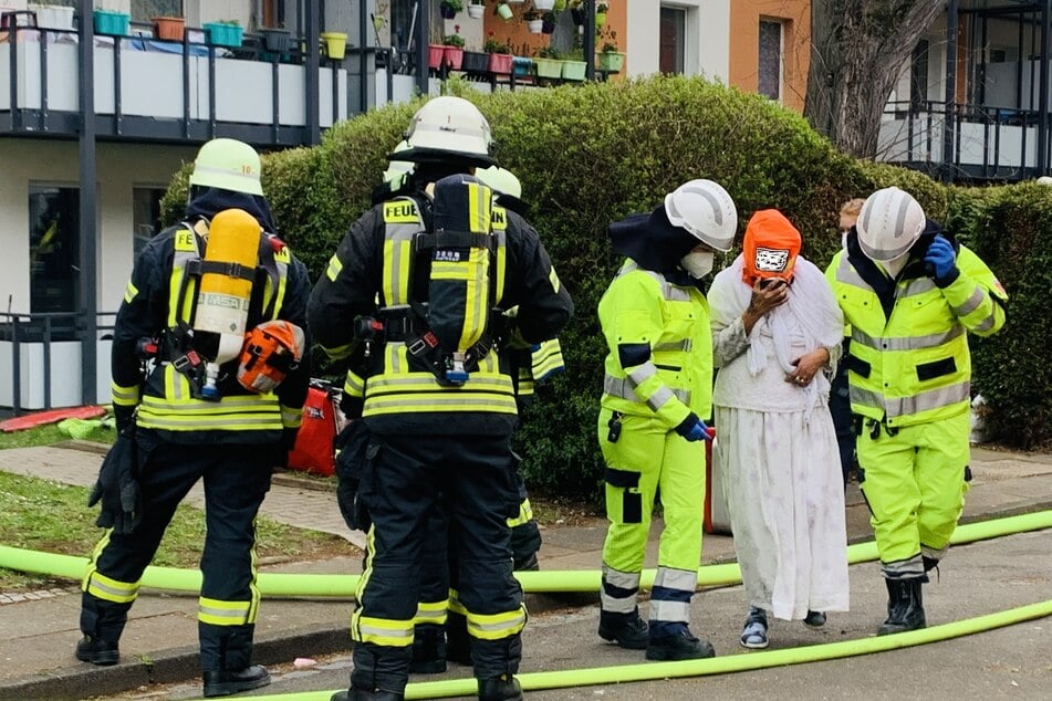 Rettungskräfte bringen einen Bewohner (2.v.r.) mit Schutzmontur in Sicherheit.