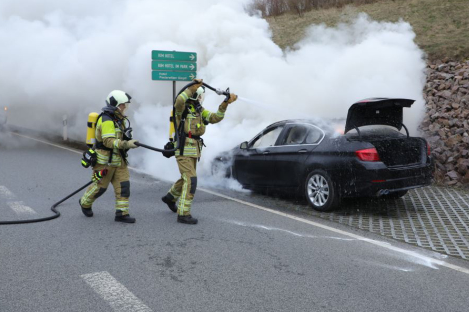 Einsatzkräfte der Feuerwehr löschen den brennenden Wagen.