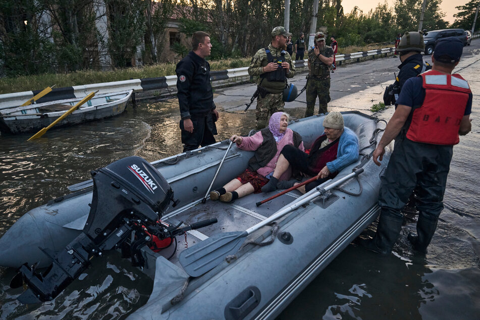 Rettungskräfte transportieren Bewohner mit Booten, die aus einem überfluteten Viertel in Cherson evakuiert werden.