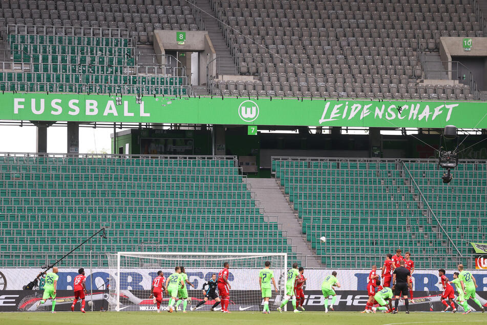 Spieler von VfL Wolfsburg und Bayern München in Aktion in der leeren Volkswagen Arena.