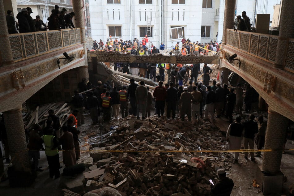 People and rescue workers gather to look for survivors under a collapsed roof after a suicide blast in a mosque in Peshawar, Pakistan.