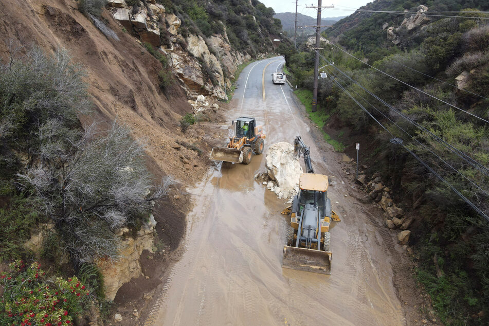 CalTrans workers chip away at a huge boulder that fell on Malibu Canyon Road amid torrential downpours in Malibu, California.