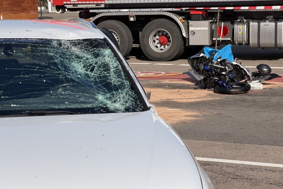Die Windschutzscheibe des Autos ist an der Fahrerseite stark beschädigt. Das Motorrad der Verstorbenen liegt zerstört auf der Straße.