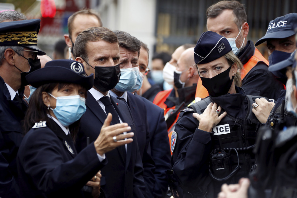Emmanuel Macron (3.v.l), Präsident von Frankreich, und Christian Estrosi (4.v.l)), Bürgermeister von Nizza, sprechen nach der Messerattacke mit Polizeibeamten.