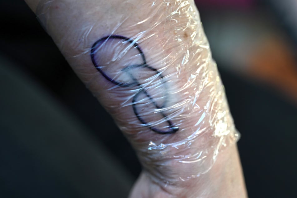 Gestochen wird das sogenannte OPT.INK-Motiv, das als Symbol für eine Organspende gilt.