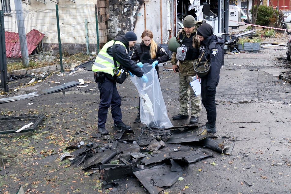 Ordnungskräfte heben nach einem russischen Drohnenangriff die Bruchstücke einer russischen Drohne auf.