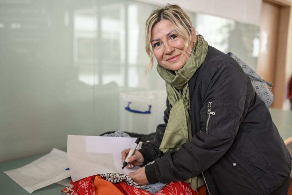 Anja Ihle (45) schreibt die Größen ihrer mitgebrachten Kleider auf Etiketten.