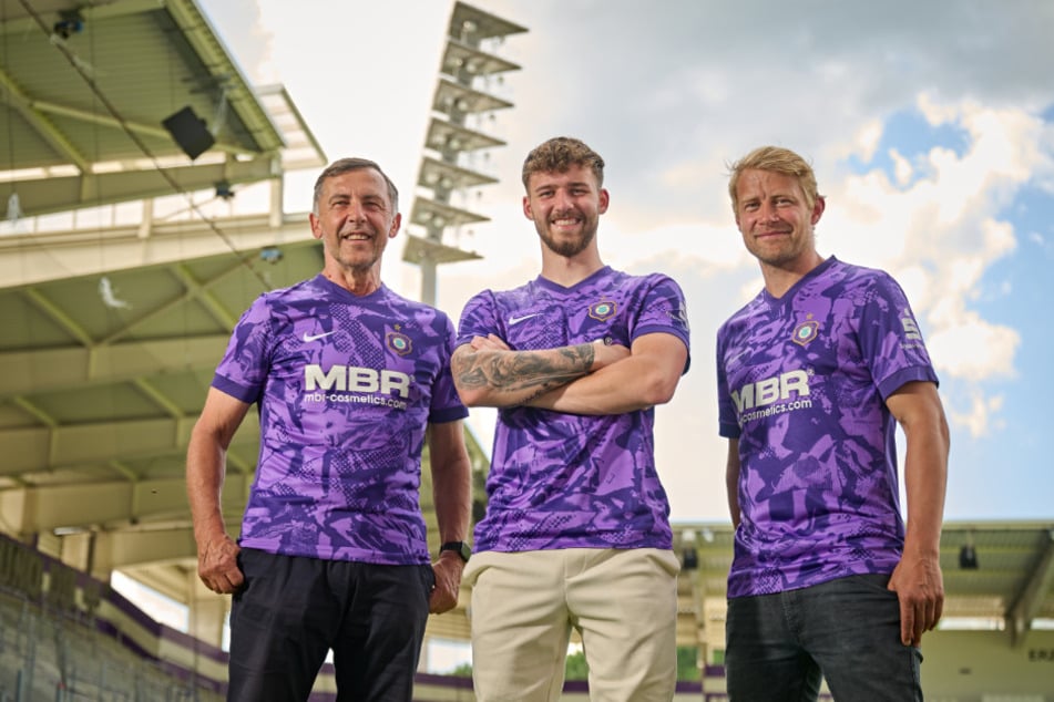 Neuzugang Eric Uhlmann (22, M.) präsentiert zusammen mit Harald Mothes (68, l.) und Jan Hochscheidt (37) das neue FCE-Trikot, das im Lila-Camouflage-Look gehalten ist.
