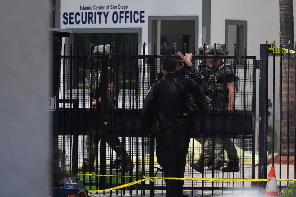 Einsatzkräfte gehen an einem mit Plane abgedeckten Opfer vorbei am Tatort nach Schüssen vor dem Islamic Center of San Diego.