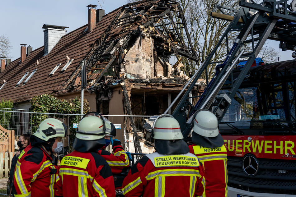 Einsatzkräfte der Feuerwehr stehen vor dem völlig zerstörten Reihenendhaus. In den Trümmern wurde eine Leiche gefunden.