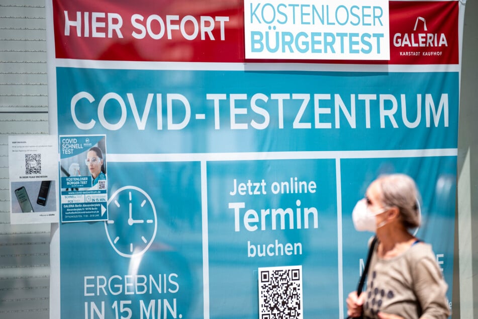 Eine Frau mit Maske läuft an einem Corona-Testzentrum am Alexanderplatz vorbei.