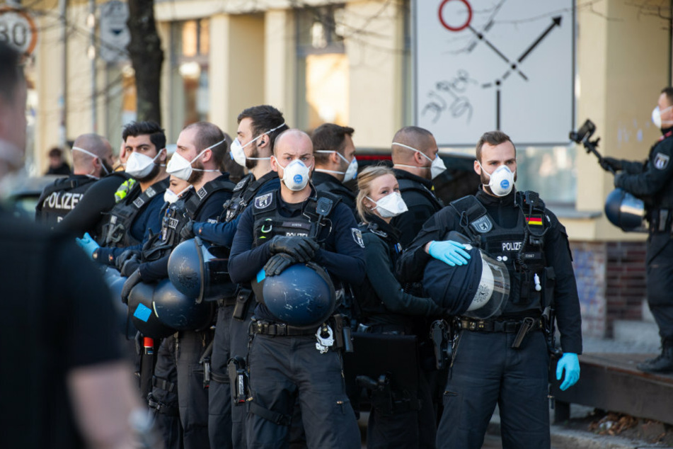 Polizisten mit Atemschutzmasken stehen auf dem Rosa-Luxemburg-Platz.