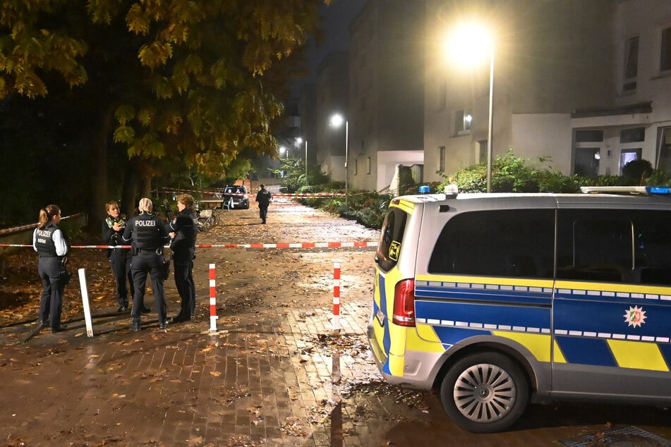 Polizisten sind an einem Wohnhaus im Einsatz. Nach dem mutmaßlichen Täter, dem Ehemann, wird gefahndet.