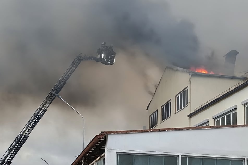 Der Feuerwehrkorb verschwindet beinahe in der dichten Rauchwolke des Feuers.