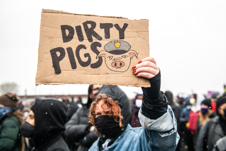 Eine Demonstrantin hält am Dienstag vor dem Hauptquartier des Brooklyn Center Police Departments ein Plakat in der Hand, auf dem "Dirty Pigs" ("Dreckige Schweine") steht und ein Schwein in Polizeiuniform abgebildet ist.