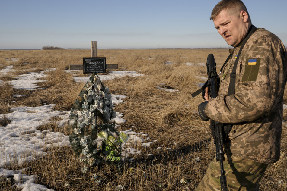 Ein ukrainischer Soldat geht an einem Kreuz in Popasna vorbei, das an einen Soldaten erinnert, der 2018 in der Nähe dieser Stelle bei Kämpfen getötet wurde.
