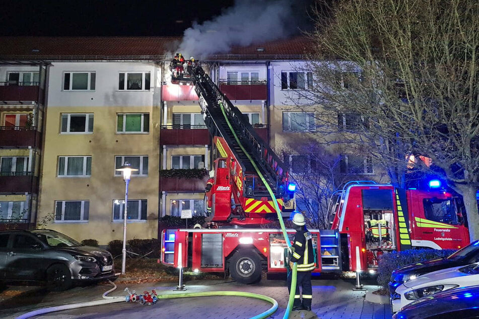 Feuerwehrleute löschen mit einer Drehleiter den Brand in der Wohnung im vierten Stock.
