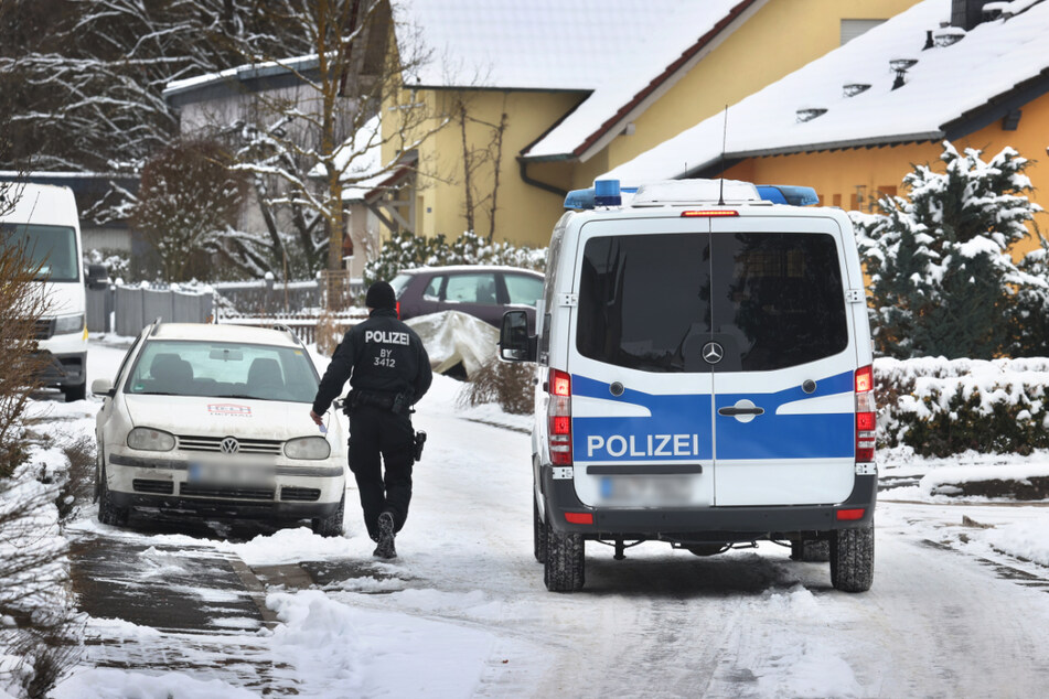 Ein Polizist läuft mit Flugblättern, auf denen die Bevölkerung um Hinweise auf einen Mordfall gebeten wird, im Ortsteil Halsbach von Tür zu Tür.
