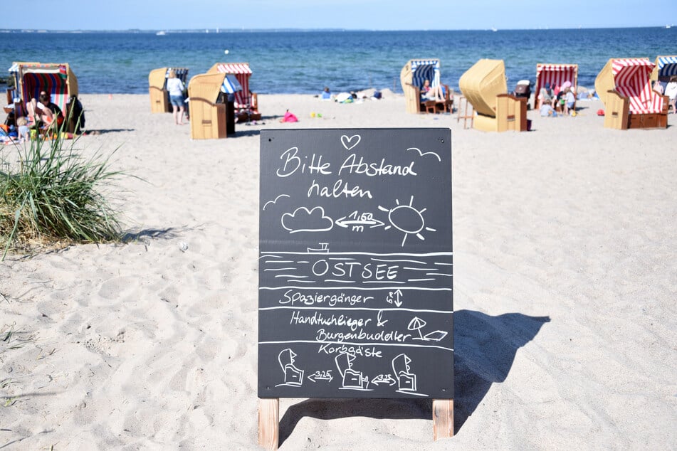 Ein Schild mit der Aufschrift "Bitte Abstand halten" steht am Zugang zum Strand an der Ostsee.