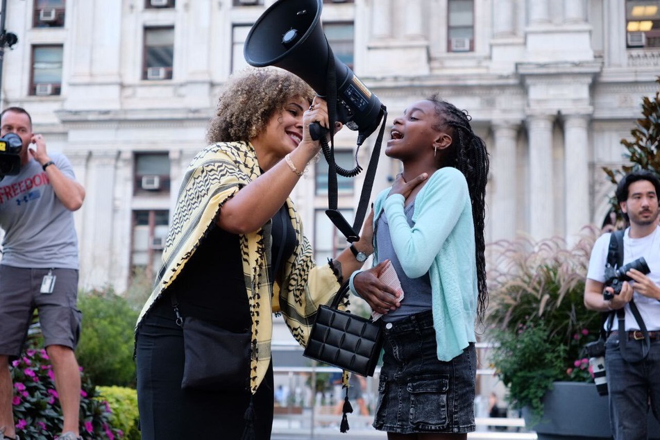 Claudia De la Cruz holds the megaphone for a young protester outside the Kamala Harris-Donald Trump debate in Philadelphia, Pennsylvania.