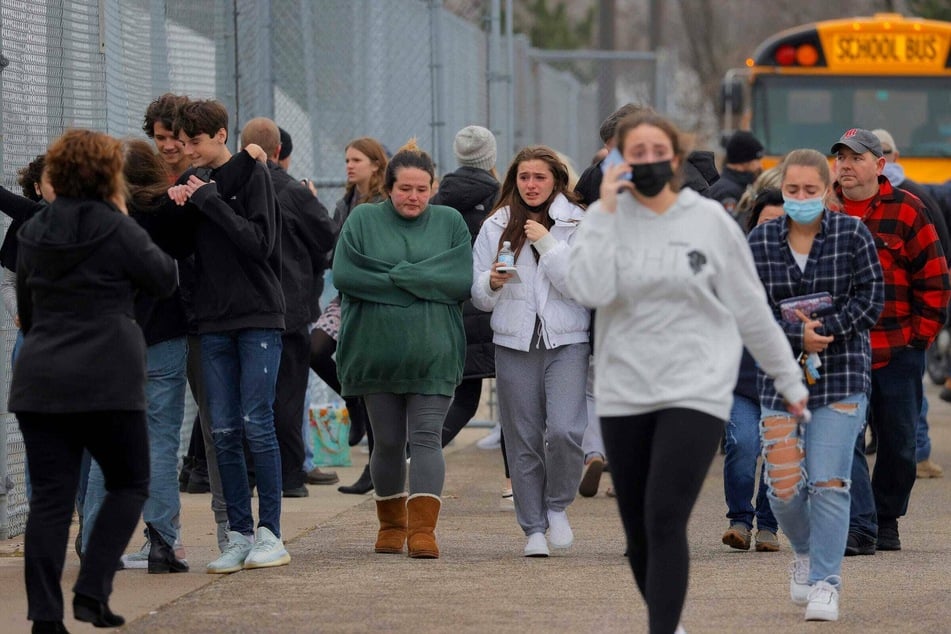 Parents walk away with their kids from the Meijer parking lot in Oxford, Michigan, where many students gathered following the shooting.