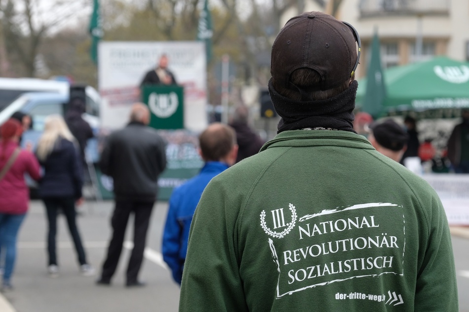 Ein Teilnehmer einer Kundgebung der rechtsextremen Partei „Der III. Weg“ trägt eine Jacke mit der Aufschrift "National revolutionär sozialistisch".