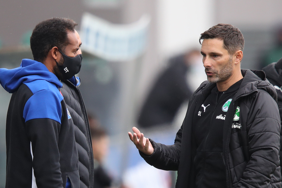 HSV-Coach Daniel Thioune (l) und der Fürther Trainer Stefan Leitl (r) unterhalten sich vor Spielbeginn.