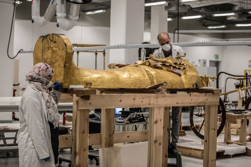 Egyptian archeologists, wearing personal protective equipment, perform restorations on the golden sarcophagus of the ancient Egyptian Pharaoh Tutankhamun (reigned between 1342-1325 BC) at the restoration lab of the newly-built Grand Egyptian Museum (GEM) in Giza on the southwestern outskirts of the capital Cairo on April 13, 2020.