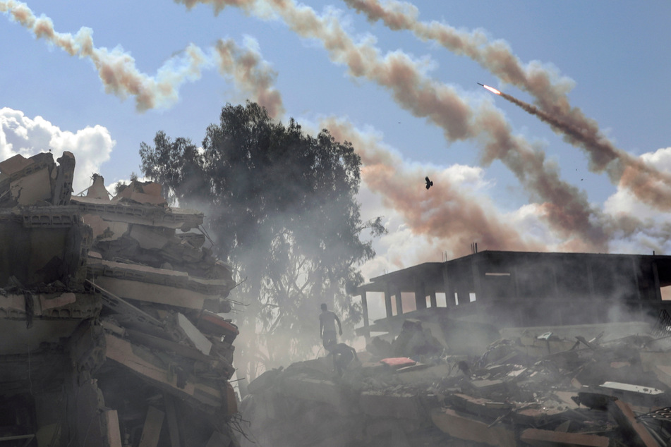 Raketen aus dem Gazastreifen werden über zerstörte Gebäude hinweg auf Israel abgefeuert.